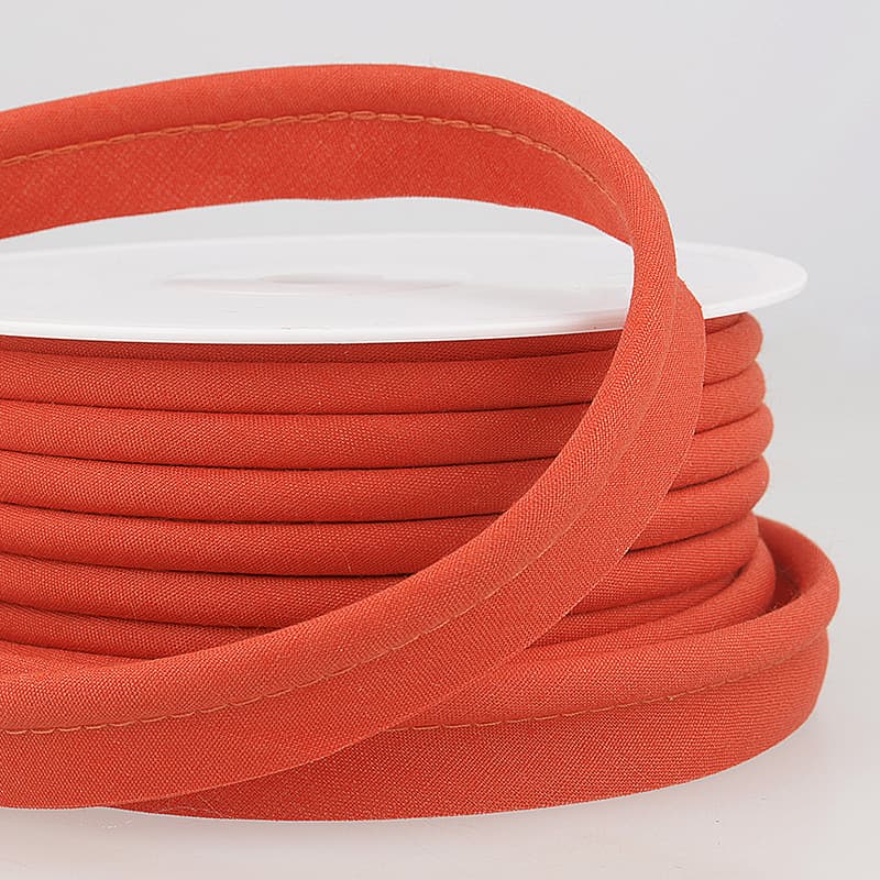 Orange coloured piping on a roll with a light grey background.