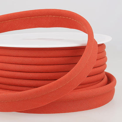 Orange coloured piping on a roll with a light grey background.