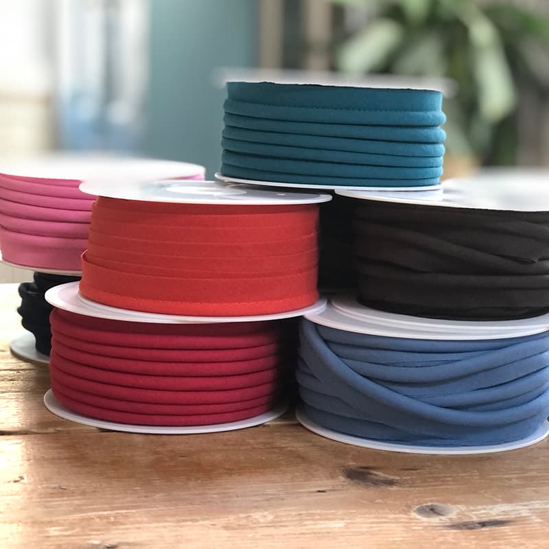 selection of piping on spools in different colours, sitting on a pine table.