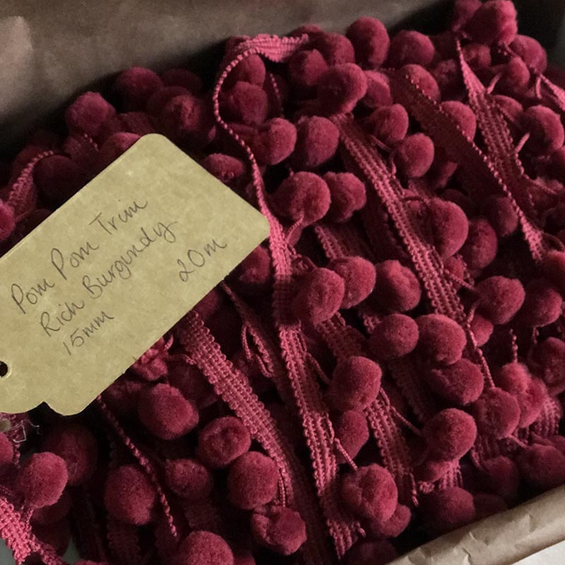 Burgundy and raspberry pom poms in box.