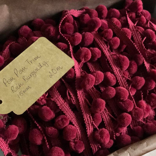 Burgundy and raspberry pom poms in box.