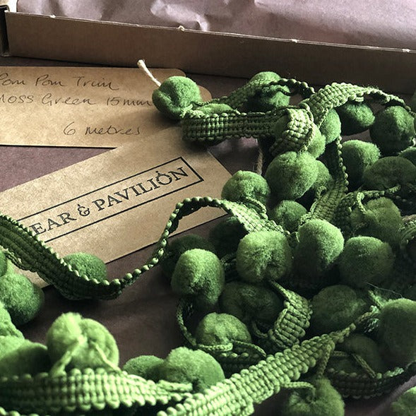 Pom pom trim in moss green shown with packaging.